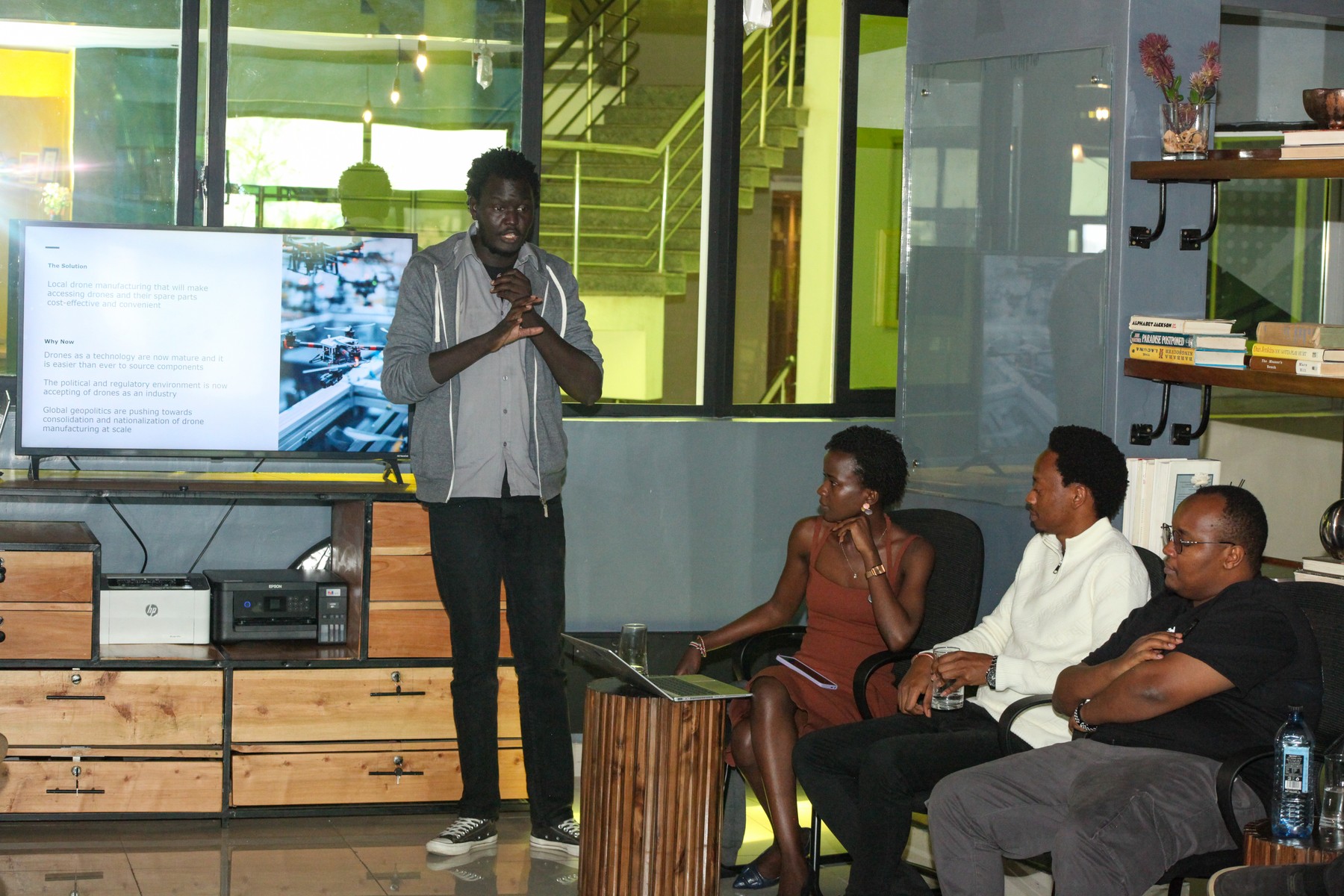 A man presenting beside a screen as others listen