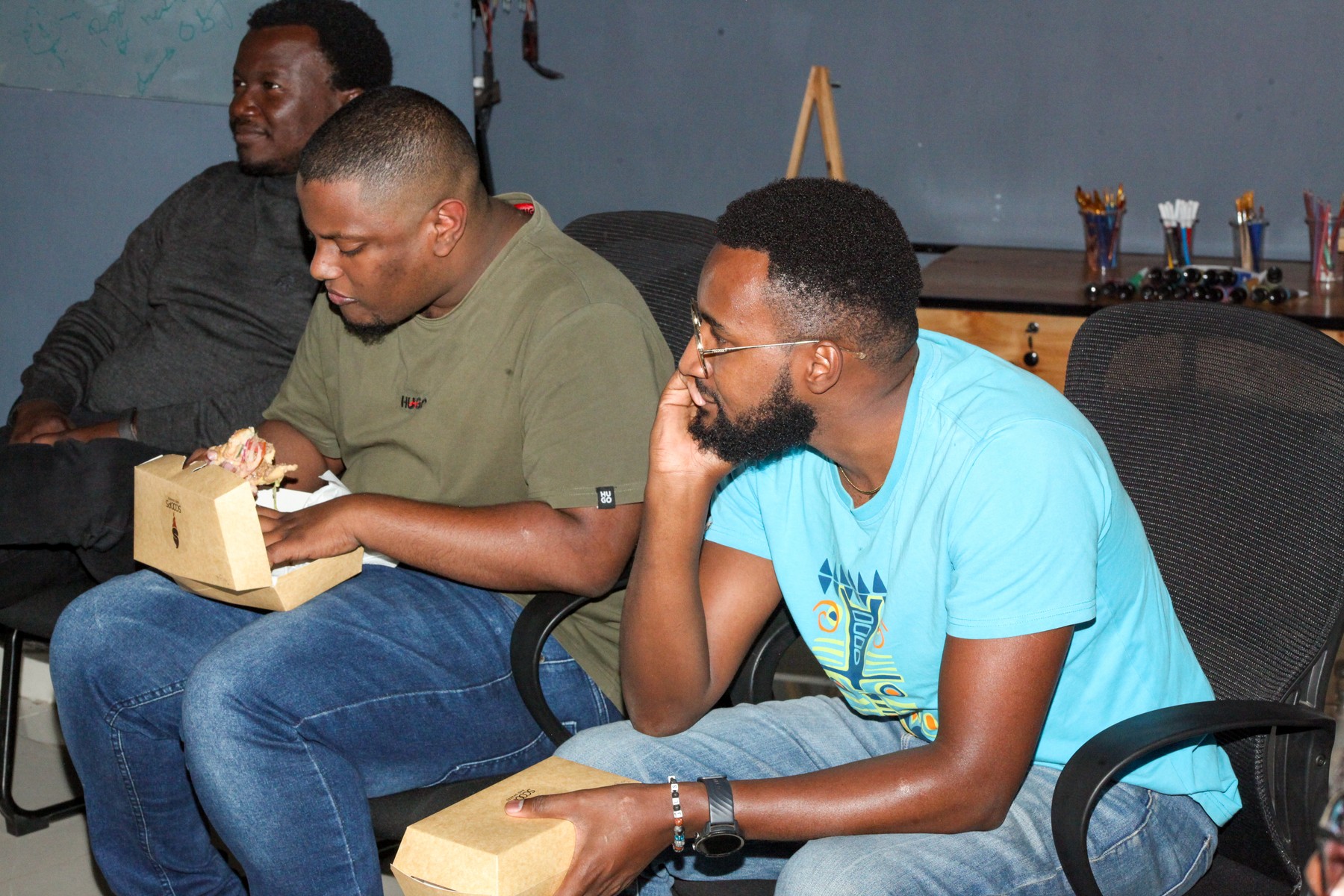 Three men sharing food and talking from their seats