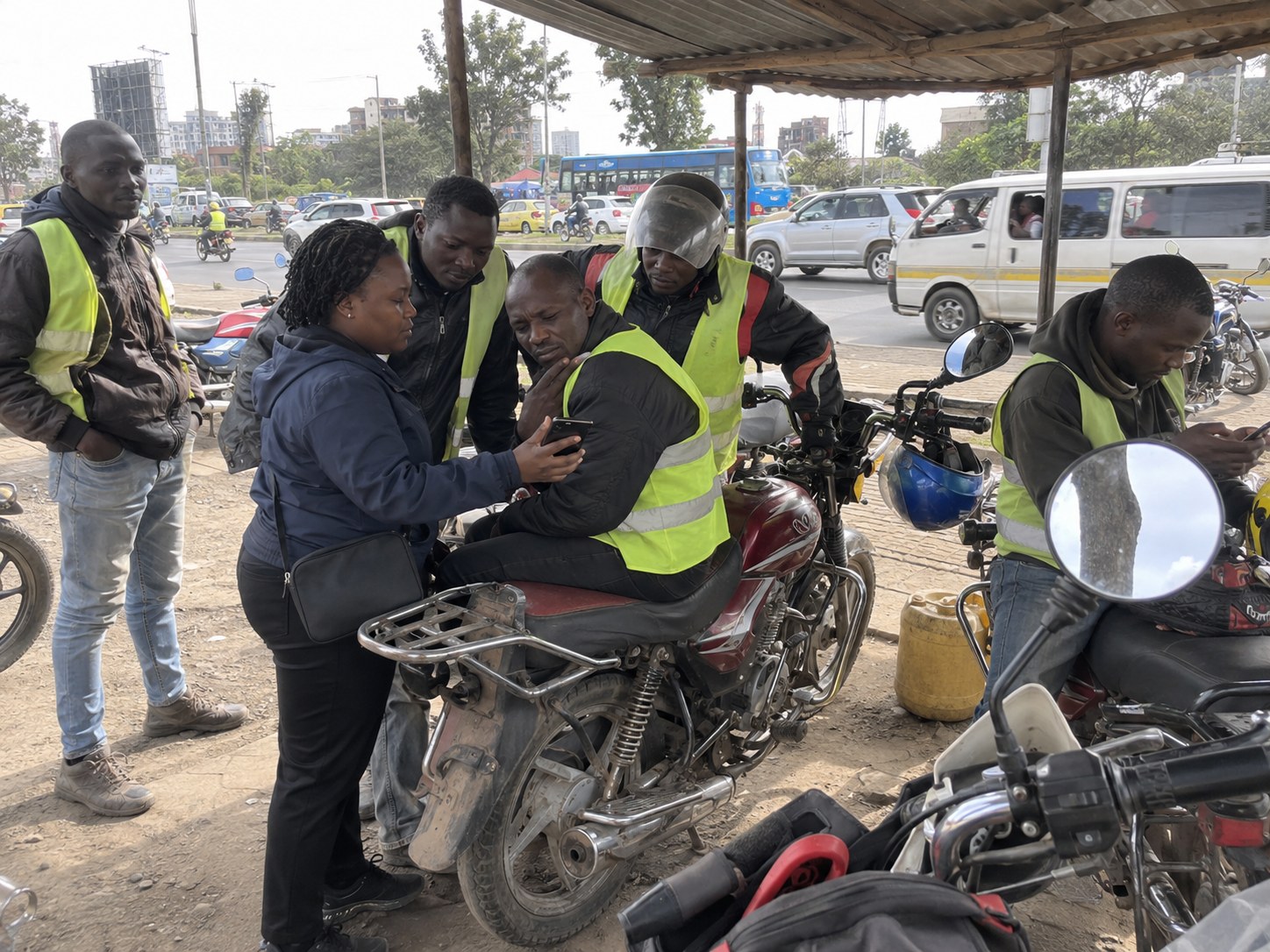 A founder showing an app on her phone to boda boda riders at their stage