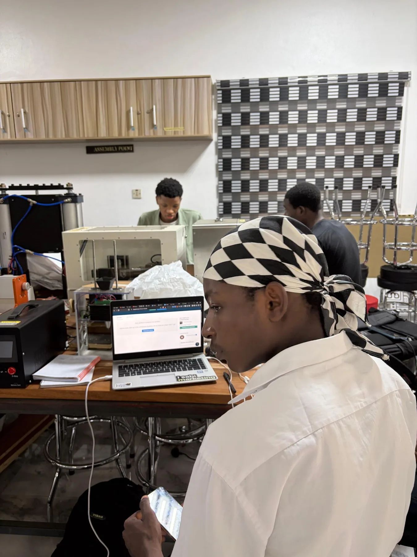 A builder in a patterned headscarf working at a laptop